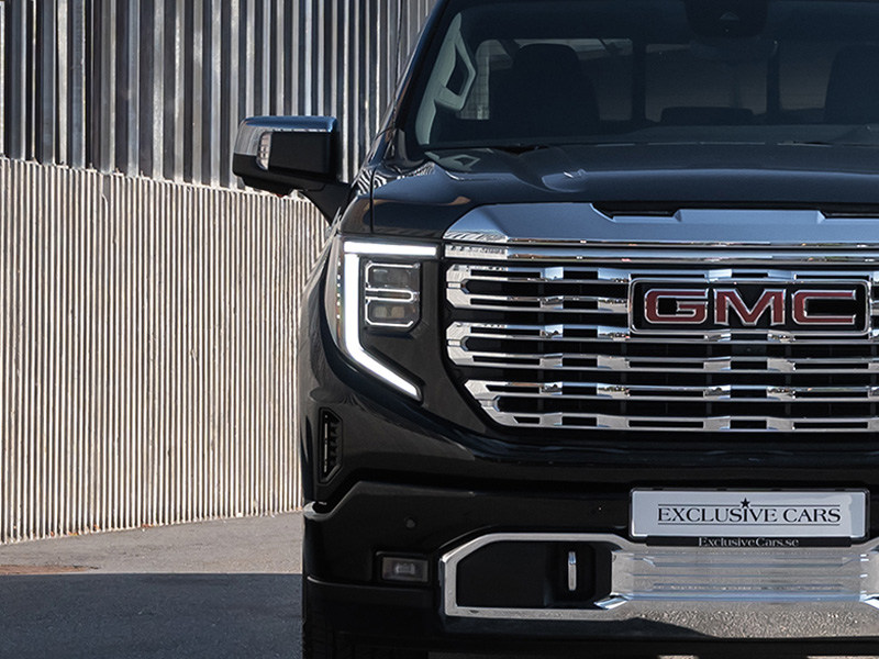 Närbild på fronten av en svart GMC-lastbil med kromgrill och LED-strålkastare.